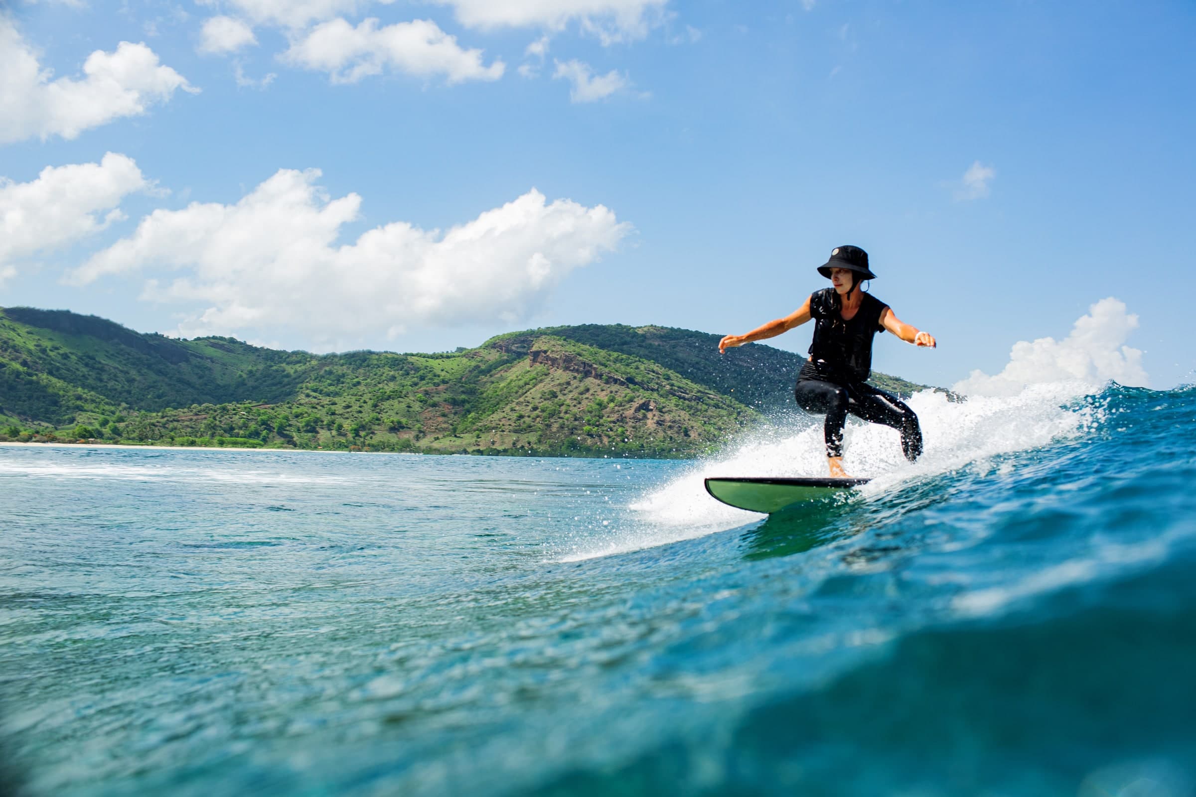 Surfer riding a wave near a green coastline